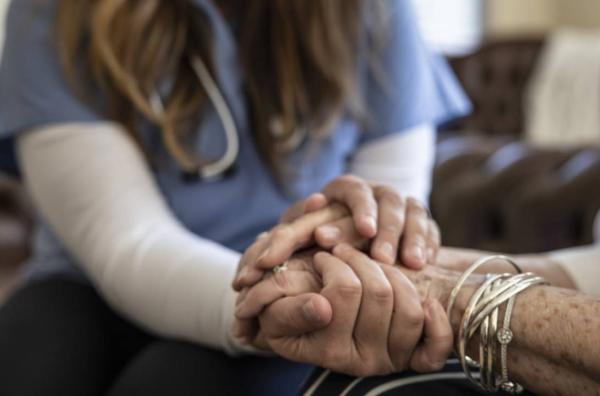 Healthcare provider holds the hands of a patient in a showing of support