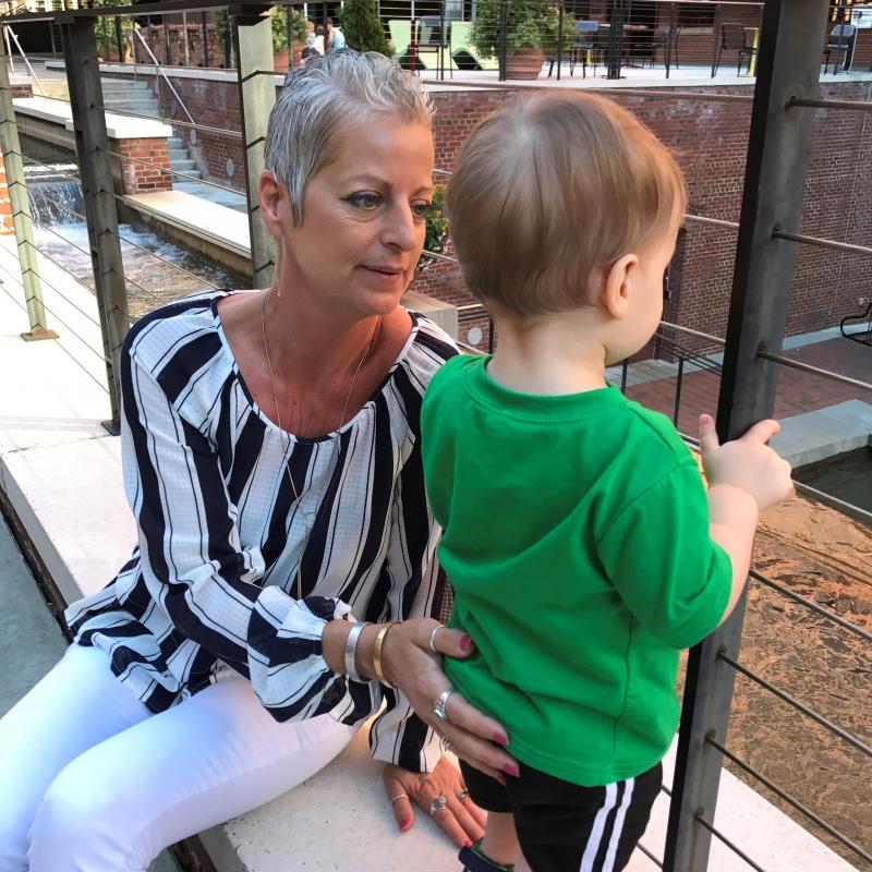 Brenda Brooks' hand is on the back of her grandson, Rocco, as he looks through a fence