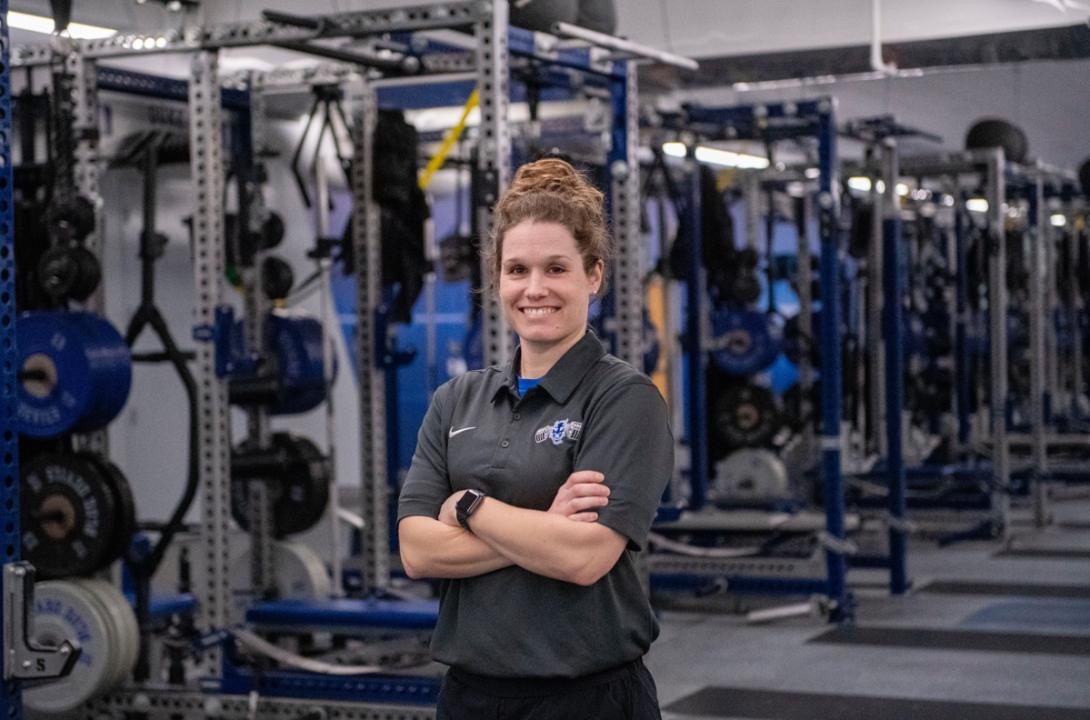 woman standing smiling with arms crossed in a weight room