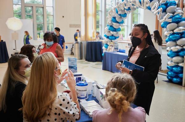 A woman speaks with presenters at an informational table at DCI Survivorship Day