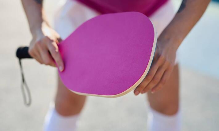 pickleball player holds pink paddle