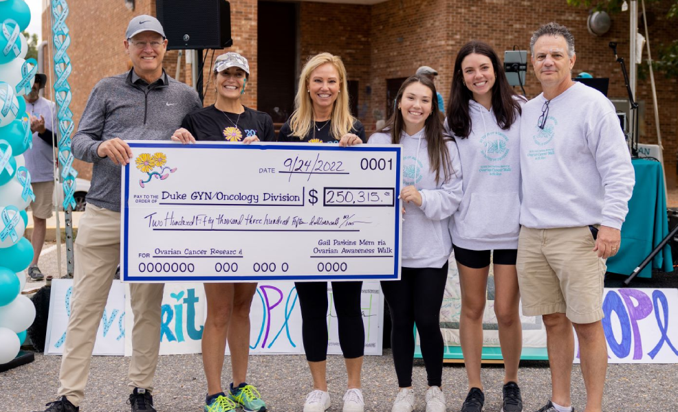 Group smiles and holds large check. 