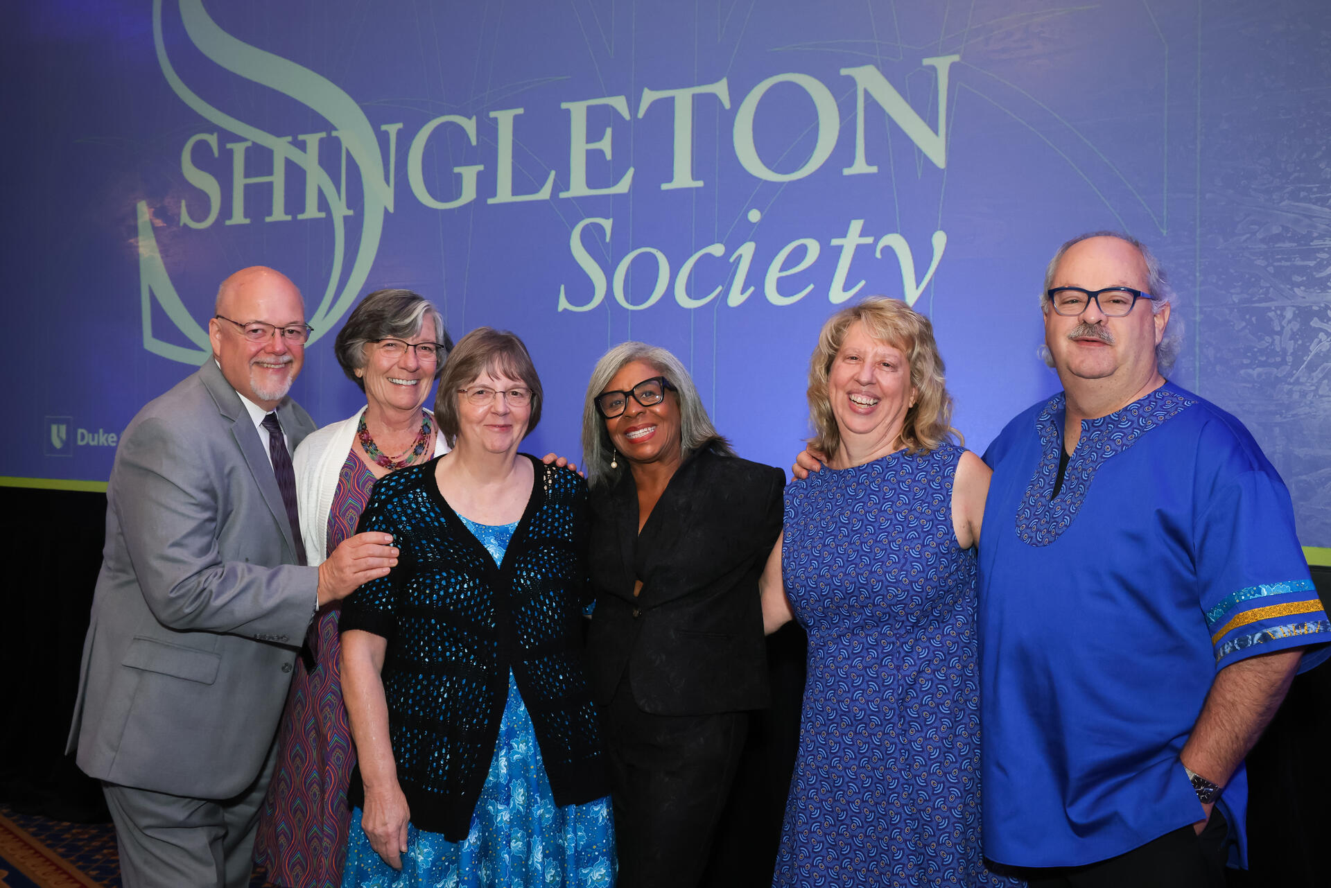 A group of people in front of a blue Shingleton Society backdrop