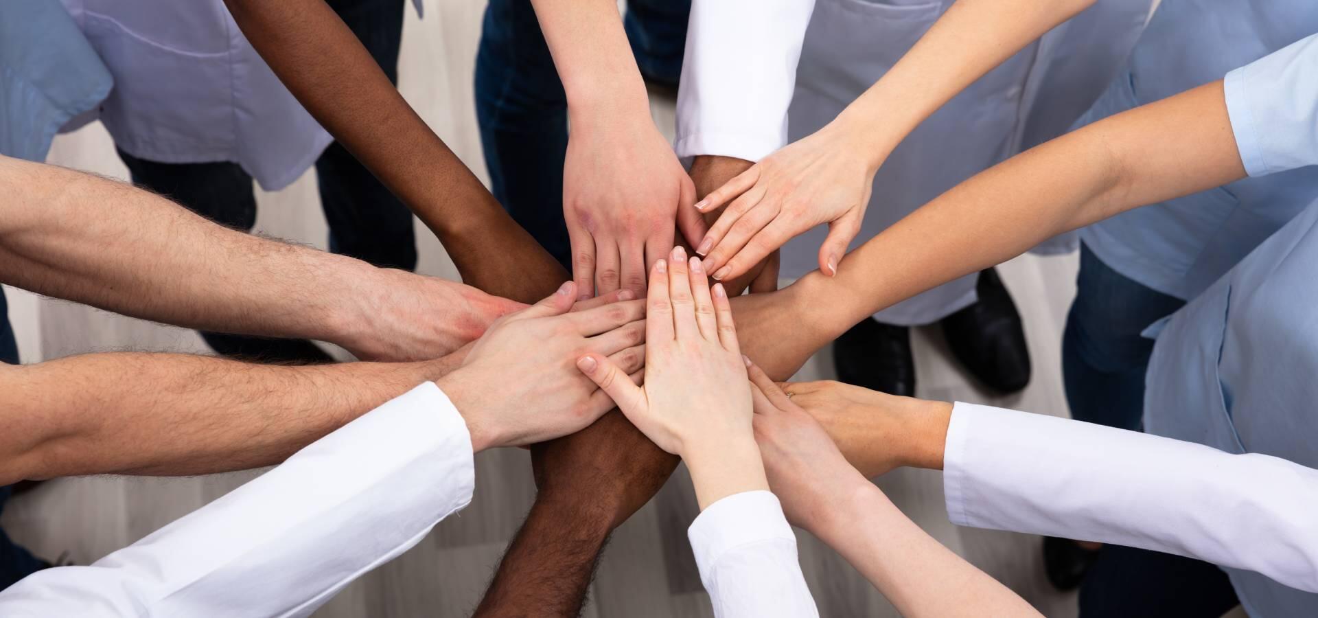  A group of diverse medical professionals stacking their hands in the middle