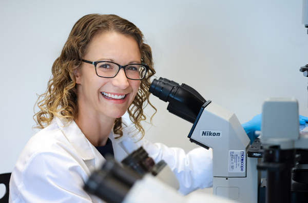 Dr. Christine Eyler looks through a microscope in her lab