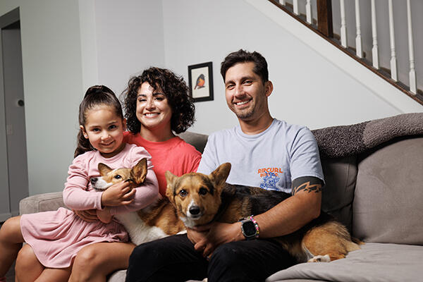 A family and their two dogs smiling on a couch.