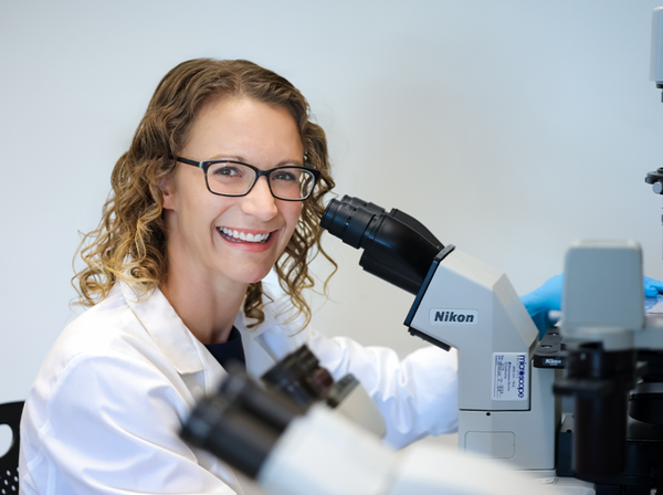 Dr. Christine Eyler looks through a microscope in her lab