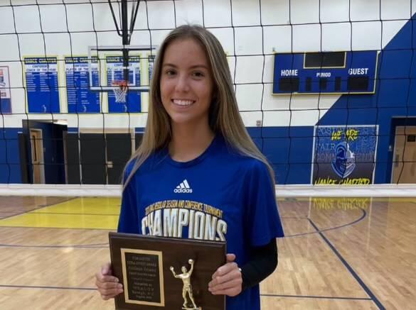 Addison Rowan smiles on the volleyball court holding a plaque