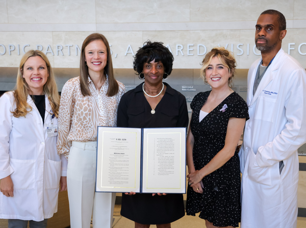 Members of the Duke Center for Brain and Spine Metastasis pose with Congresswoman Valerie Foushee (NC-04) as she presents a copy of the resolution she introduced to Congress to establish Brain and Spine Metastasis Awareness Month.