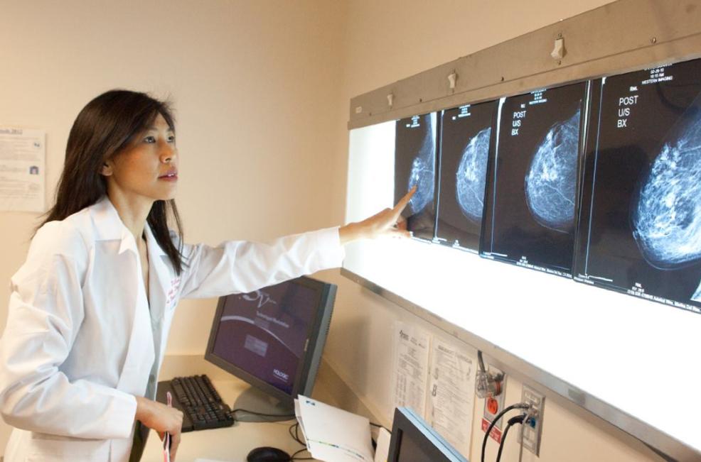 Woman in white lab coat looking at breast x-rays