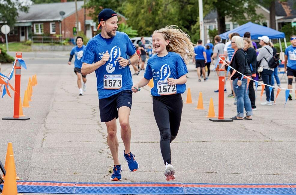 Man running with adolescent girl and smiling at each other