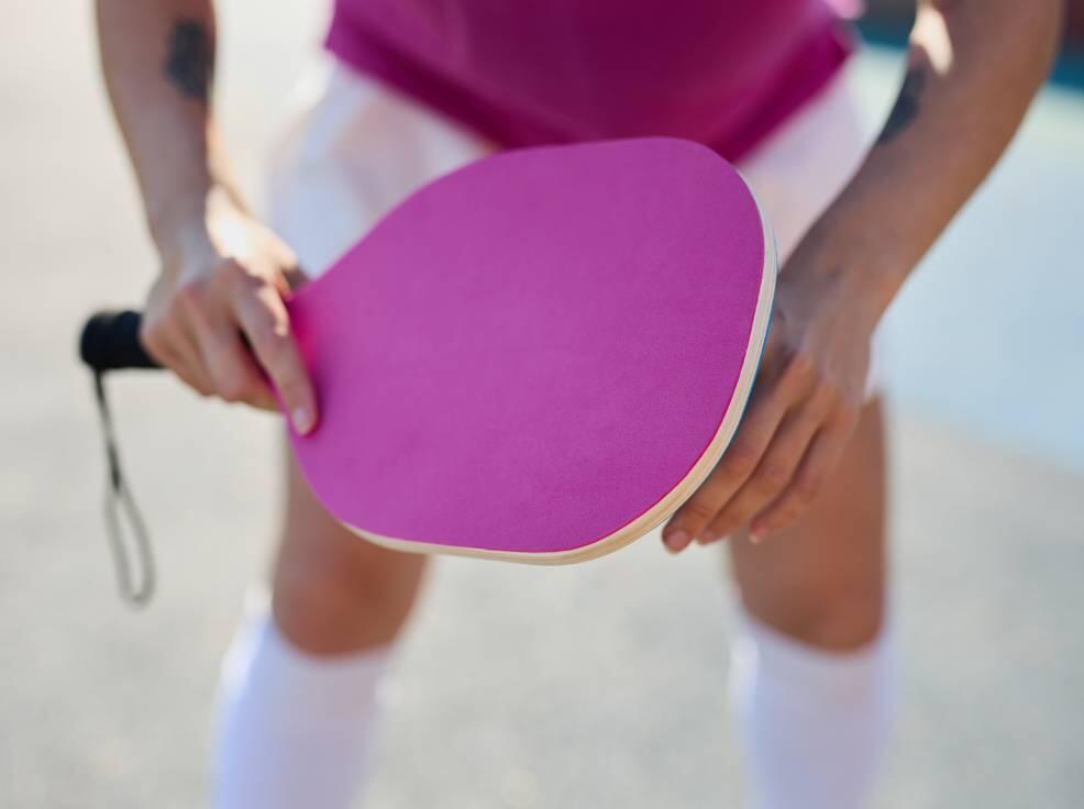 pickleball player holds pink paddle