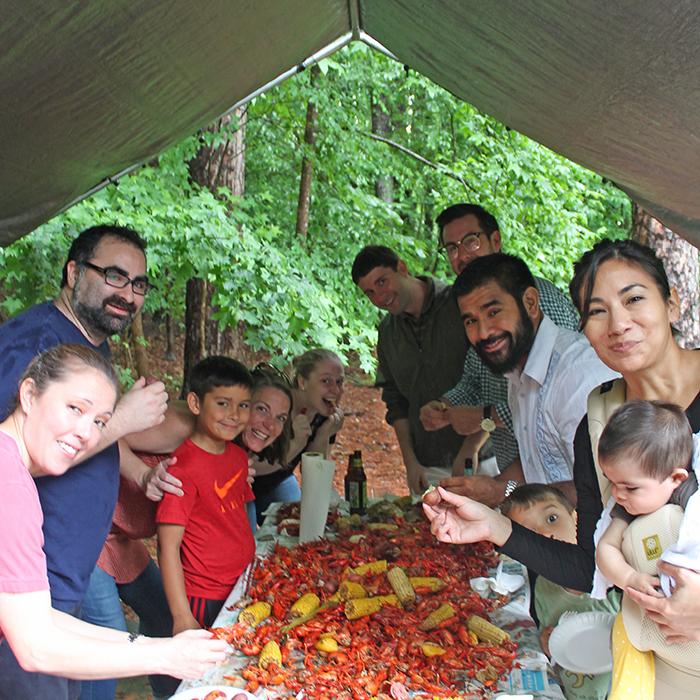 A group of people huddle around a table with a pile of boiled crawfish.